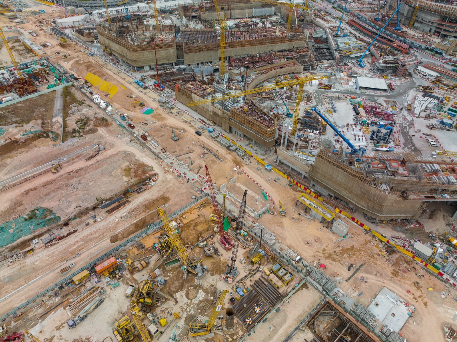 Aerial view of a large-scale active construction site with multiple cranes and structures under way
