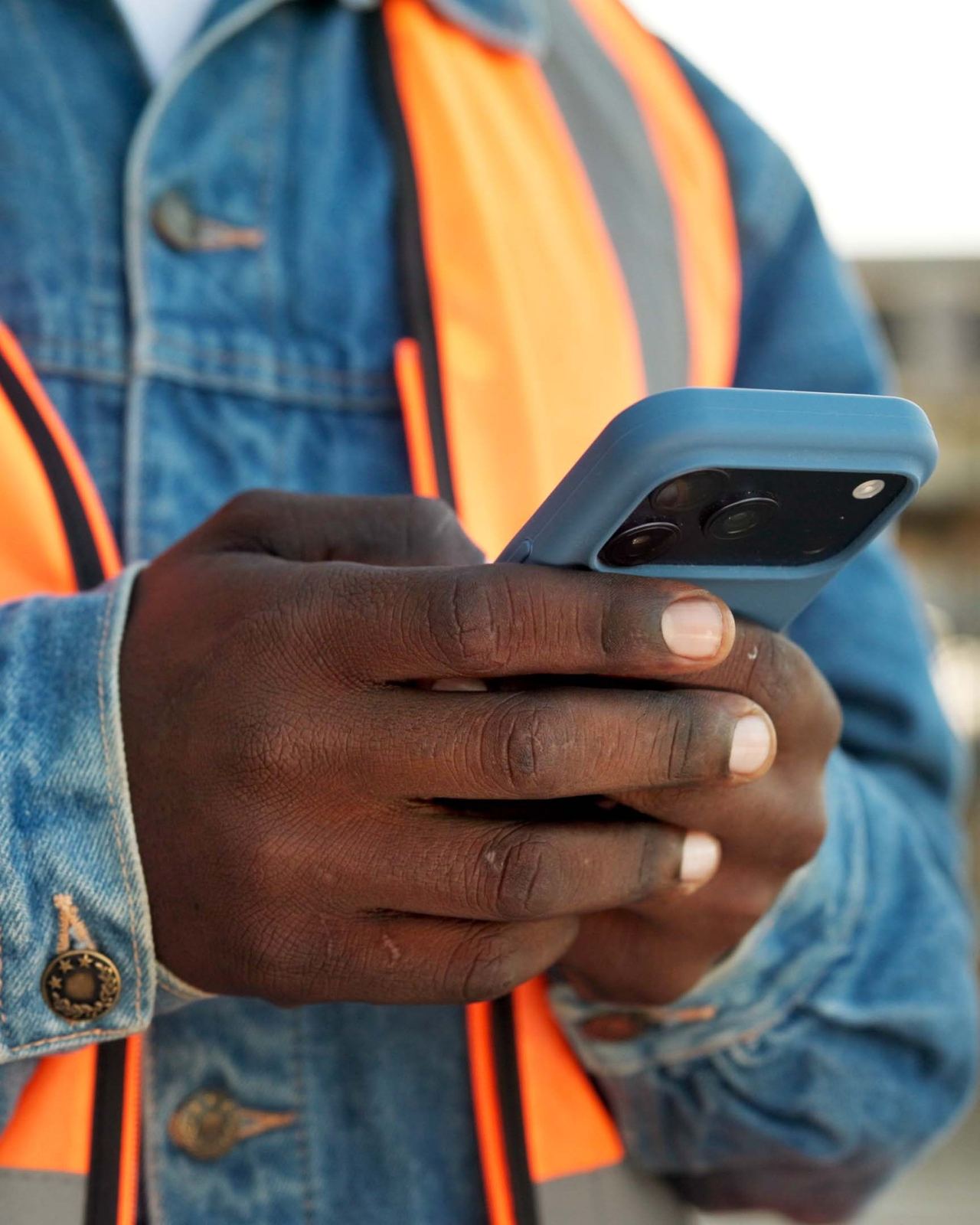 A construction worker in a hi-vis vest checking a message on his phone on site