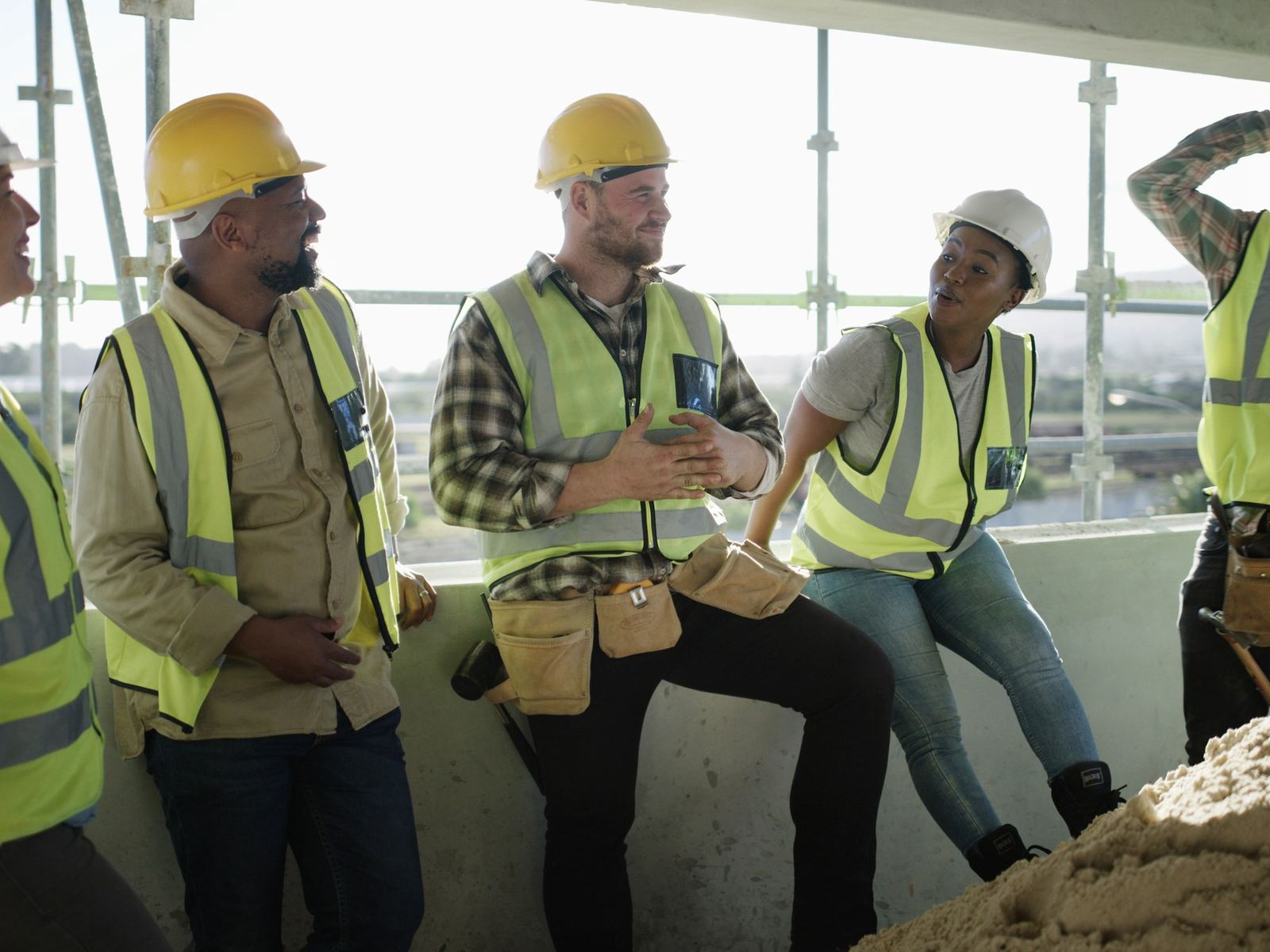 A diverse crew of construction workers sharing a laugh together on an upper floor of a building under construction